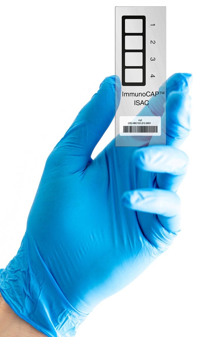 Microcipul ImmunoCAP ISAC tinut in mana cu manusa, cu cele patru pozitii de reactie